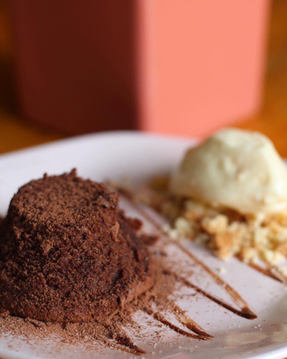 Bolo de chocolate com sorvete de creme e farofa doce num prato raso