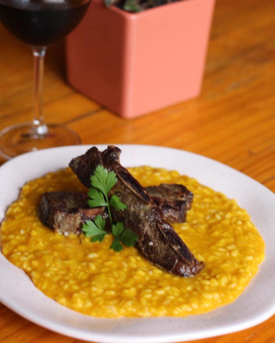 Risoto amarelo com tiras de carne e salsinha, com taça de vinho ao fundo